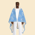 Model wearing the Cozy Blue Hooded Sherpa Blanket featuring the signature Frozen ZZZ's pattern and white sherpa-lined hood.