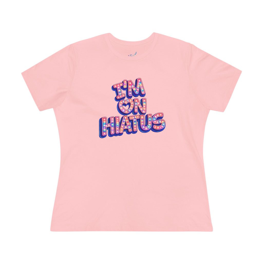 A light pink short-sleeve crewneck t-shirt featuring a colorful graphic on the chest that reads 'I'M ON HIATUS' in a bubbly, patterned font with blue and red outlines.