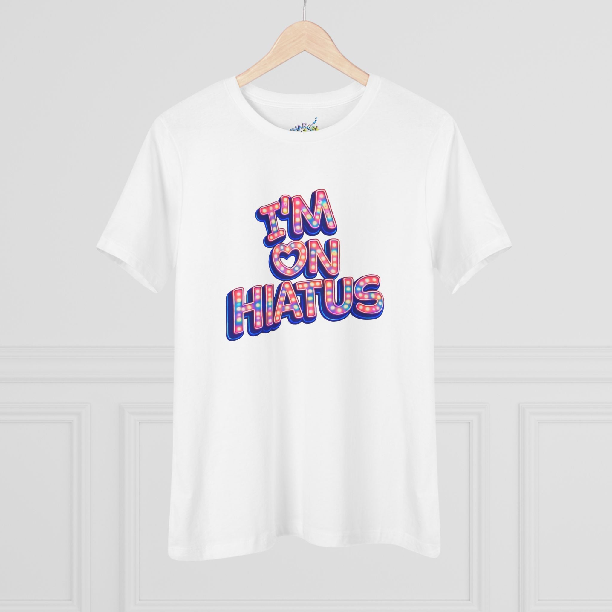 White short-sleeve crewneck graphic t-shirt featuring the "I'm On Hiatus" marquee design, hanging on a wood hanger against a light gray wall