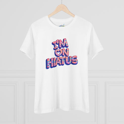 White short-sleeve crewneck graphic t-shirt featuring the "I'm On Hiatus" marquee design, hanging on a wood hanger against a light gray wall